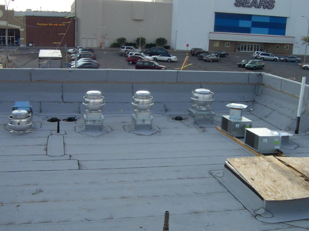 A gray roof of a shopping building adorned with various equipment.