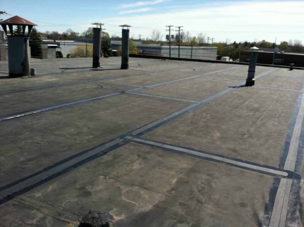 large black roofing tiles placed over an industrial flat roof.