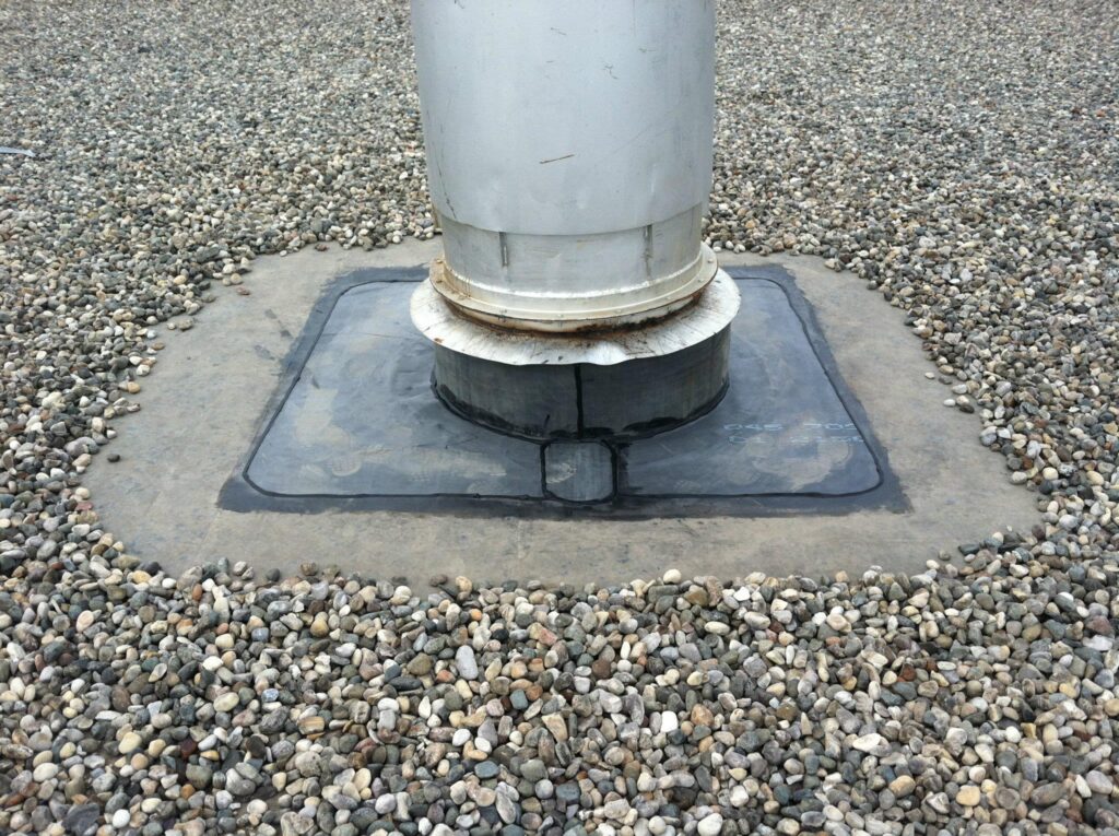 A ventilation pipe on gravel, covered with waterproof material, providing air circulation.